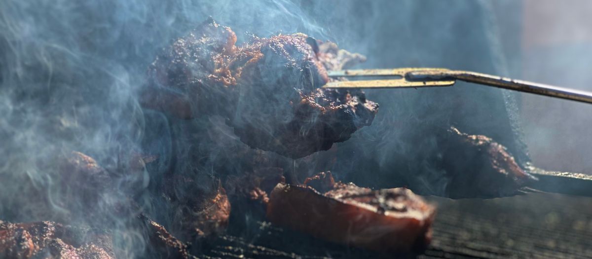 A pellet grill with a digital controller and a phone app nearby.